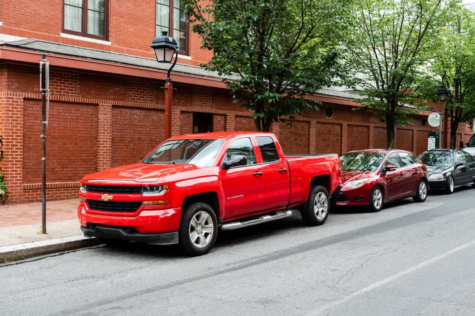Red Chevrolet truck parked on street in front of two small sedans in Philadelphia, Pennsylvania.